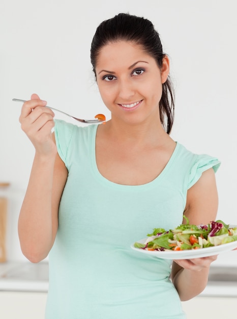 Mujer joven con ensalada mirando a la cámara