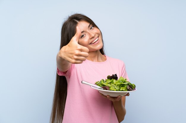 Foto mujer joven con ensalada con los pulgares arriba porque algo bueno ha sucedido