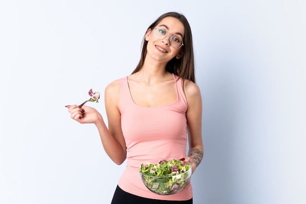 Foto mujer joven con ensalada sobre pared aislada