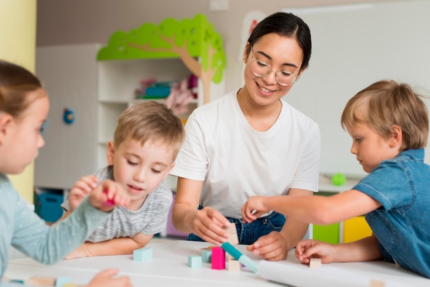 Foto mujer joven enseñando a los niños a jugar con juego colorido