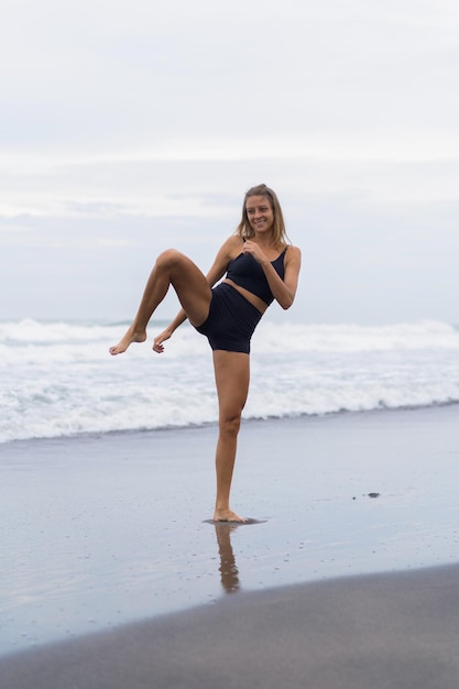 Mujer joven entrena en la playa, taekwondo, patadas, spinner, patada circular.