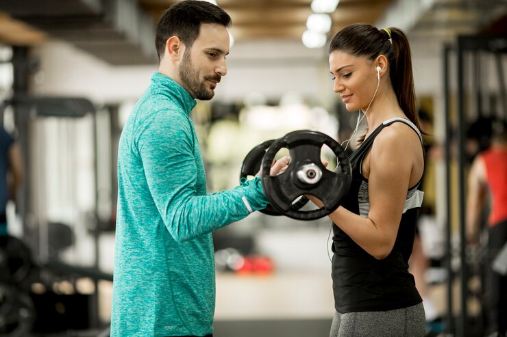 Foto mujer joven con entrenador personal en el gimnasio