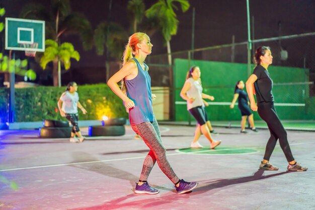 Mujer joven en un entrenamiento grupal en la cancha de baloncesto por la noche