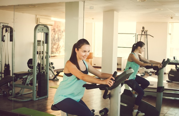 mujer joven entrenando en bicicleta en el gimnasio