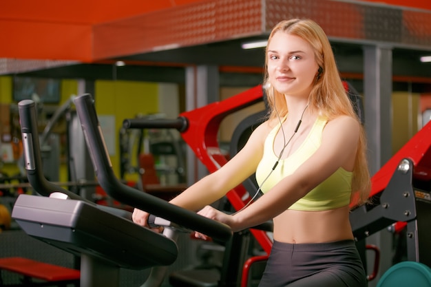 Mujer joven entrenando en bicicleta en el gimnasio