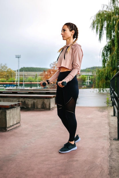 Mujer joven entrenando con pesas al aire libre