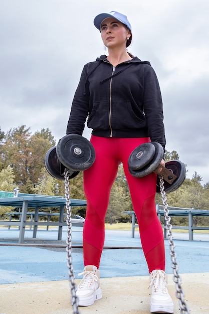 Mujer joven entrenando con pesas en el parque