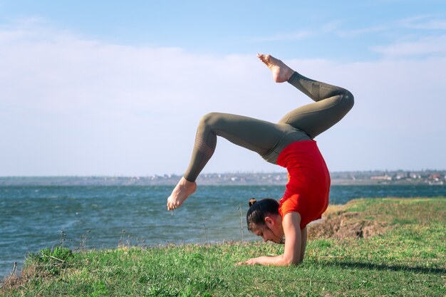 Mujer joven entrenando un yoga al aire libre