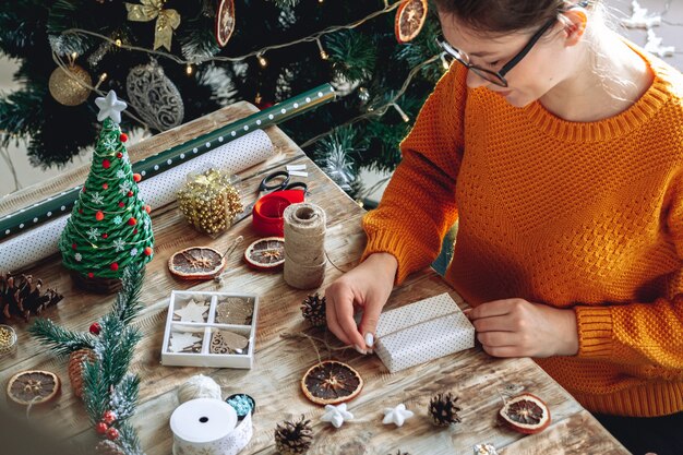 Mujer joven envolver el regalo de Navidad en la mesa