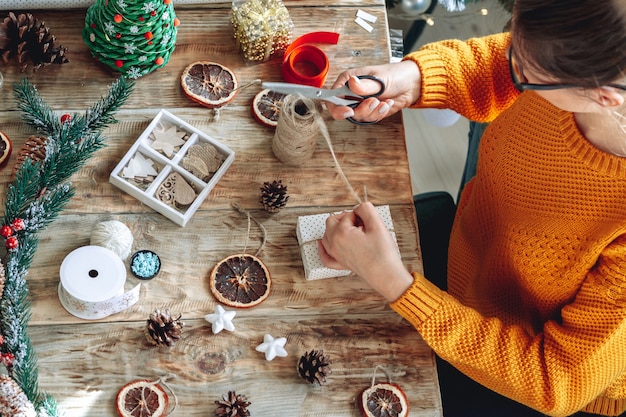 Mujer joven envolver el regalo de Navidad en la mesa