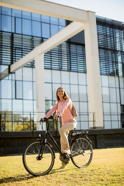 Mujer joven, equitación, e, bicicleta, en, ambiente urbano