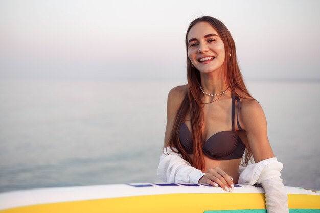 Mujer joven, es, proceso de llevar, paddle board, en la playa