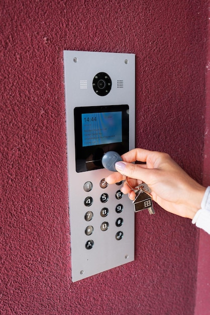 Una mujer joven escribe el código del apartamento en el panel de intercomunicación electrónica abre la puerta con una tecla táctil la pantalla para ver información Concepto de protección y seguridad