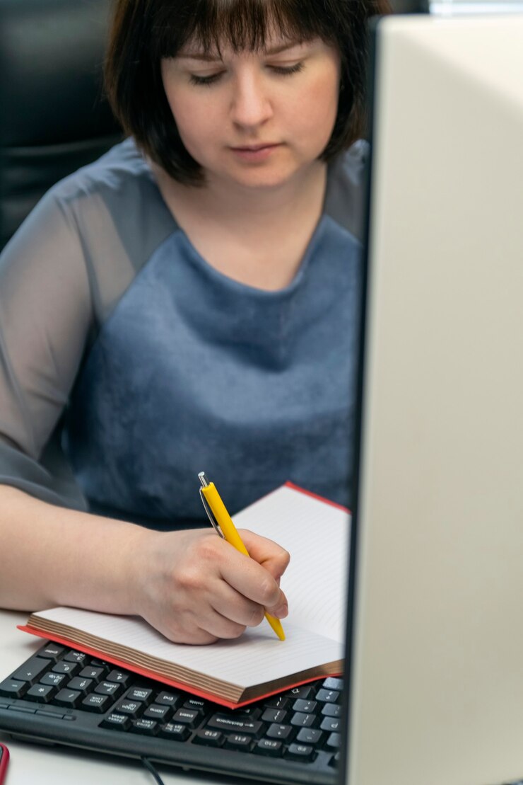 Foto mujer joven escribe en el cuaderno en el lugar de trabajo. secretaria en el trabajo. administrador de tareas. programación de tareas.