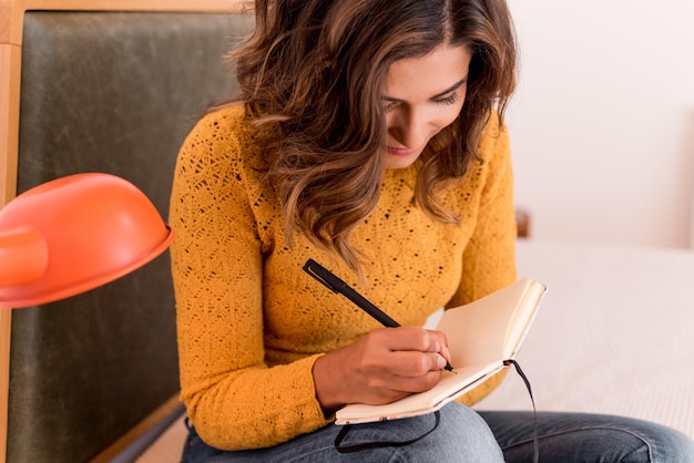 Mujer joven escribiendo algunas notas en su diario