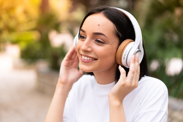 Mujer joven escuchando música al aire libre
