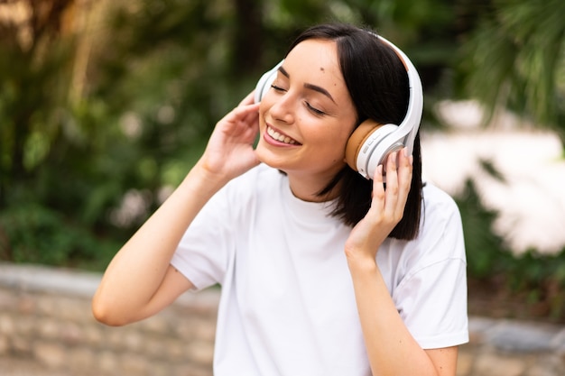 Mujer joven escuchando música al aire libre