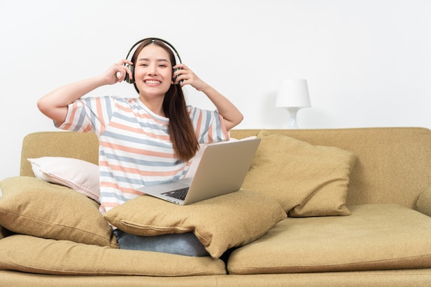 Mujer joven escuchando música con auriculares en casa