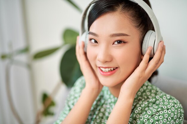 Mujer joven escuchando música mientras se relaja en el sofá en casa