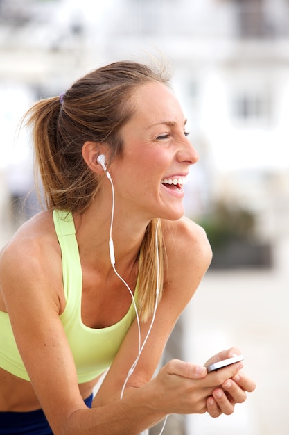 Mujer joven escuchando música con reproductor de MP3 y auriculares