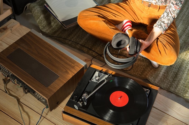 Mujer joven escuchando música en un sistema HiFi con auriculares amplificadores de tocadiscos y discos de vinilo LP en una sala de escucha