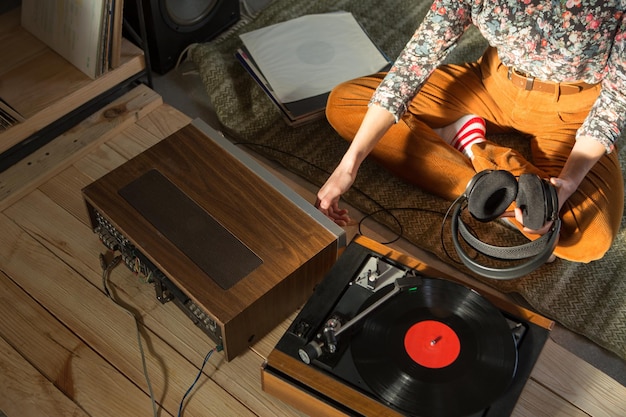 Mujer joven escuchando música en un sistema HiFi con auriculares amplificadores de tocadiscos y discos de vinilo LP en una sala de escucha