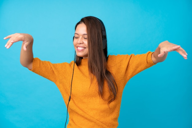 Mujer joven escuchando música sobre pared aislada