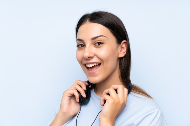Mujer joven escuchando música sobre pared azul aislado