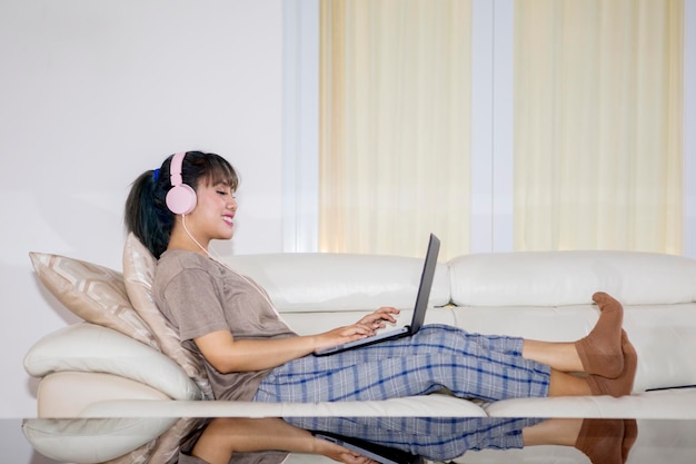 Mujer joven escuchando música en el sofá