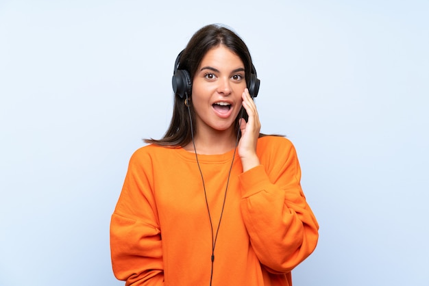 Mujer joven escuchando música con sorpresa y expresión facial conmocionada