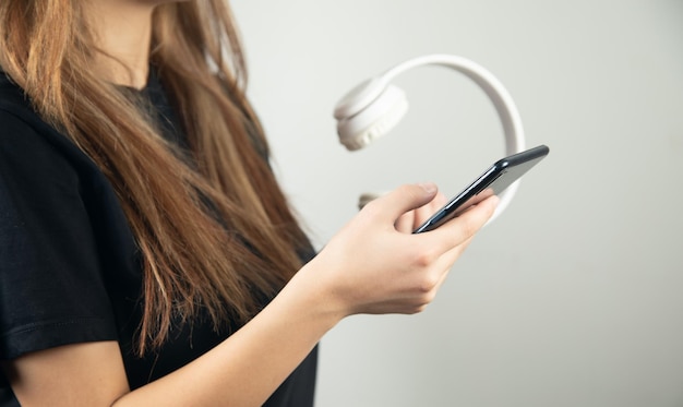 Mujer joven escuchando música con teléfonos inteligentes y auriculares inalámbricos