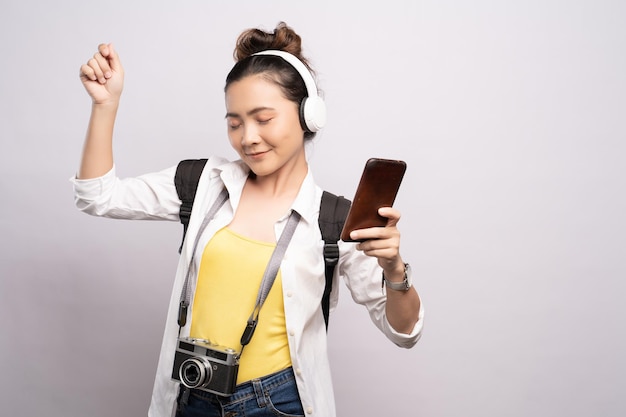 Mujer joven escuchando música a través de auriculares mientras baila contra un fondo blanco