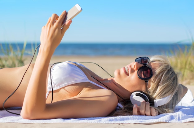 mujer joven, escuchar música, en, auriculares, en la playa