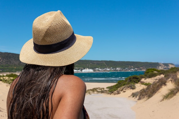 Mujer joven de espaldas con un sombrero mirando al mar Espacio de copia Enfoque selectivo