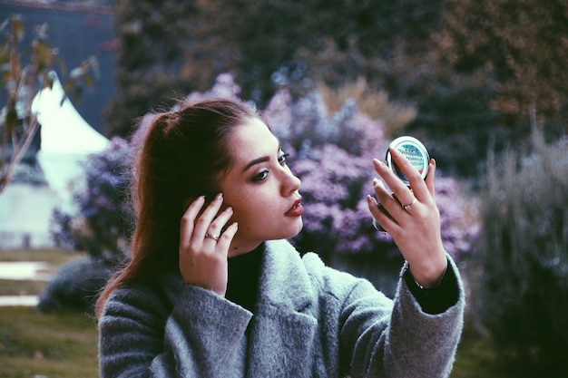 Foto mujer joven con espejo de mano al aire libre