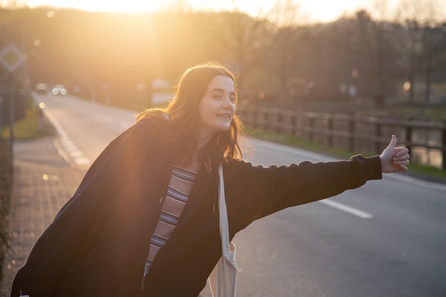 Una mujer joven esperando el transporte en automóvil al atardecer