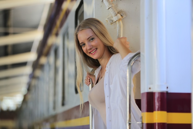 Mujer joven esperando en tren vintage, relajado y despreocupado en el andén de la estación