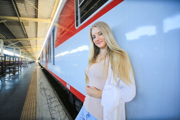 Mujer joven esperando en tren vintage, relajado y despreocupado en el andén de la estación