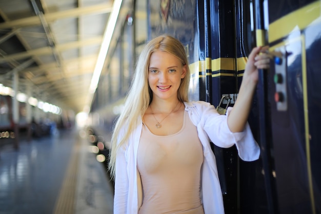 Mujer joven esperando en tren vintage, relajado y despreocupado en el andén de la estación