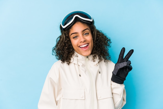 Foto mujer joven esquiador afroamericano aislado alegre y despreocupado mostrando un símbolo de paz con los dedos.