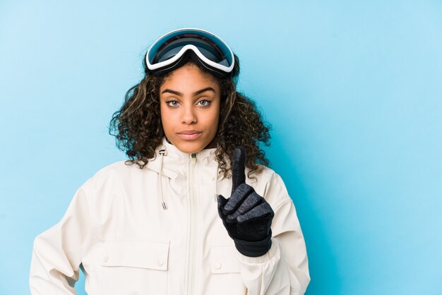 La mujer joven del esquiador del afroamericano aisló mostrar el número uno con el dedo.