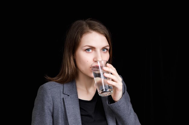 Mujer joven está bebiendo agua pura del vaso