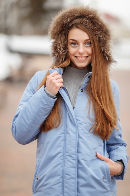 Mujer joven está caminando en el parque de invierno. Parque de invierno en la nieve. Concepto de fotografía de publicidad de ropa.