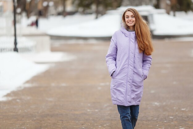 Mujer joven está caminando en el parque de invierno.