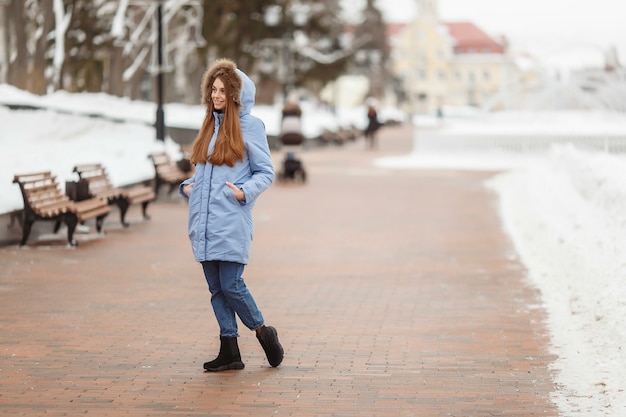 Mujer joven está caminando en el parque de invierno.