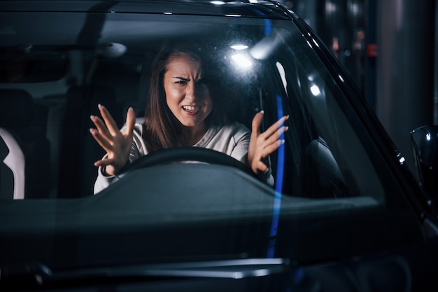 La mujer joven está dentro del automóvil moderno nuevo.