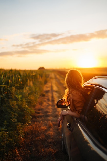 Mujer joven está descansando y disfrutando de la puesta de sol en el coche Estilo de vida viajes turismo naturaleza vida activa