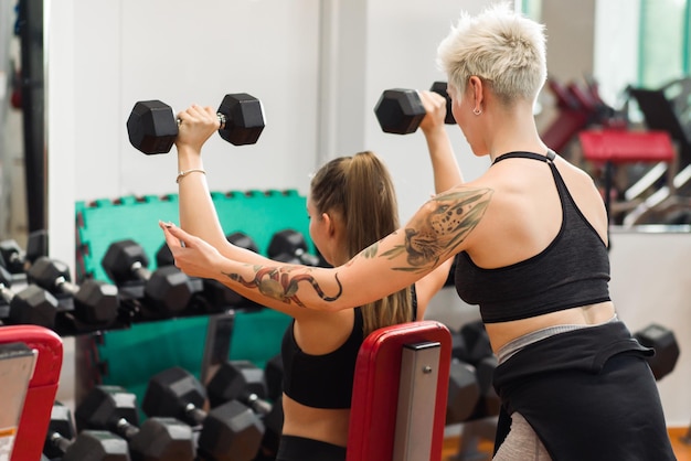 Una mujer joven está haciendo fitness con un entrenador en el gimnasio.