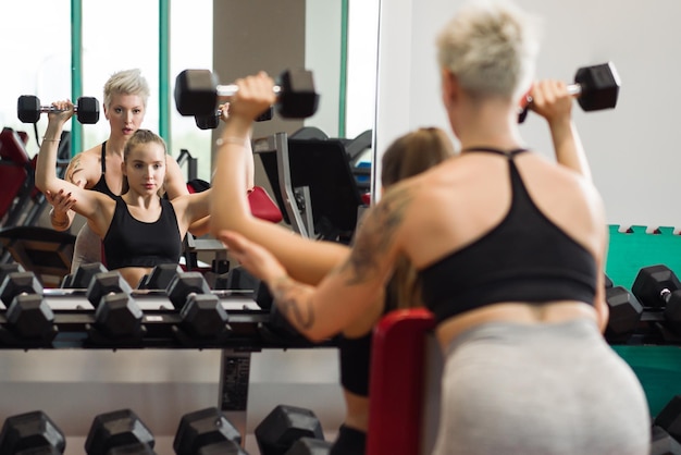 Una mujer joven está haciendo fitness con un entrenador en el gimnasio.