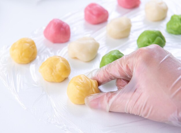 La mujer joven está haciendo una receta colorida de pastel de luna de piel de nieve de dulce postre salado tradicional de pastel de luna nevado para el estilo de vida de cierre del Festival de Medio Otoño